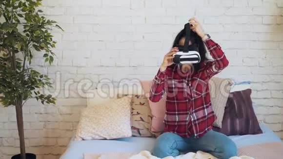 年轻的白人女性穿着虚拟现实眼镜在白色的房间绿色的树和床视频的预览图