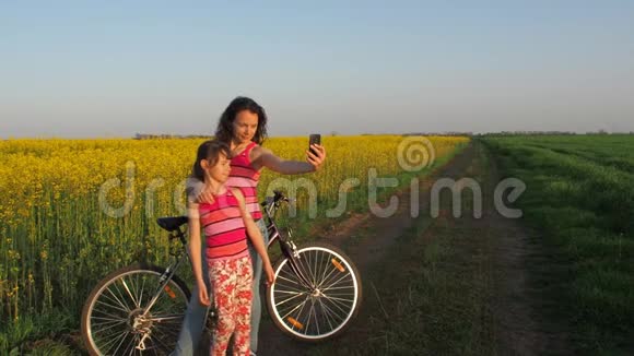 女人和一个孩子在大自然中做自拍一个快乐的母亲和她的女儿在农村被拍照骑自行车的人视频的预览图