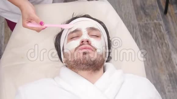 男人水疗的概念在一家美容院一个年轻人脸上戴着化妆面具视频的预览图