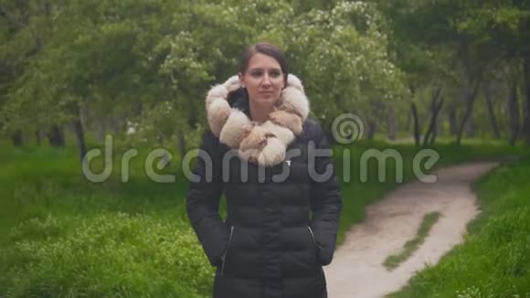 一个穿着暖和的黑色夹克的女孩穿过树林女孩跟着相机视频的预览图