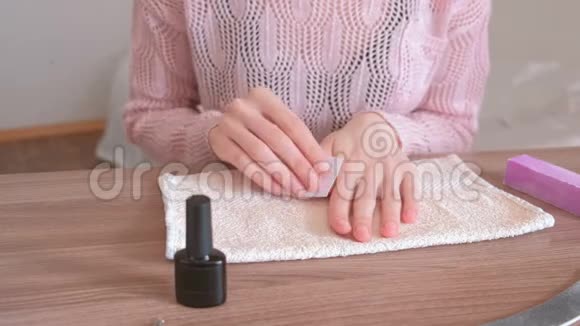 女人用无棉布擦拭指甲然后再涂上一层紫胶特写的手视频的预览图