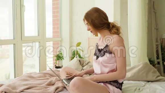 女博主坐在窗前家中的床上写一篇文章视频的预览图