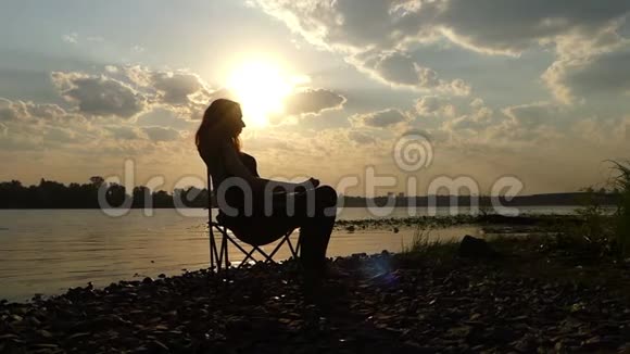 怀孕的女人在斯隆莫的夕阳下抚摸她的肚皮坐着视频的预览图