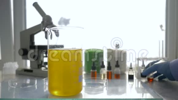 科学家在现代实验室特写镜头中用试剂在大玻璃中进行化学反应视频的预览图