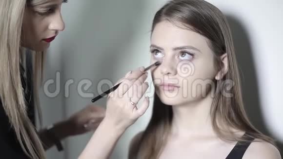 化妆师使用矫正器年轻女孩化妆粉底视频的预览图