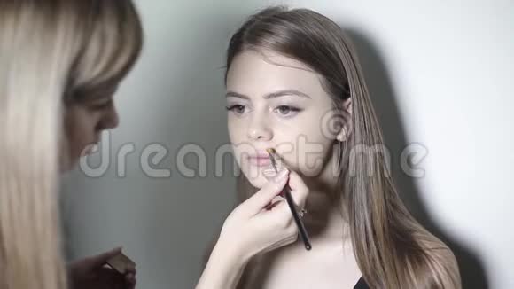 化妆师使用矫正器年轻女孩化妆粉底视频的预览图