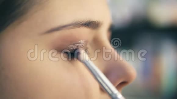 特写视角的专业化妆师用化妆刷涂抹眼影假面贴有浅棕色视频的预览图