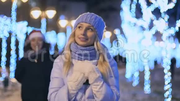 戴着圣诞老人帽子的年轻女孩带着礼物她的朋友感到惊讶视频的预览图