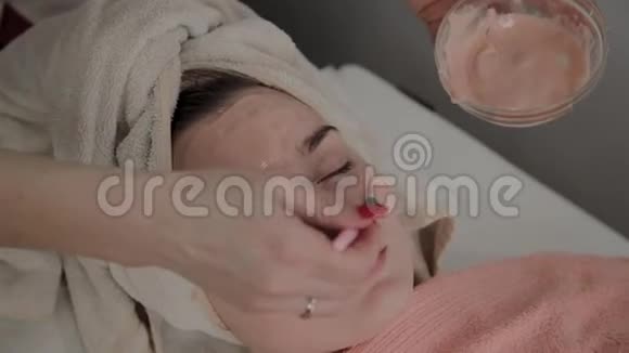 一位专业的美容师用面罩给一个带刷子的年轻女孩美容学的新概念视频的预览图