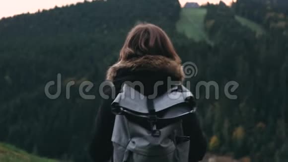 镜头跟随年轻女孩徒步旅行者走在户外的背景森林景观与高大的树木在山上视频的预览图