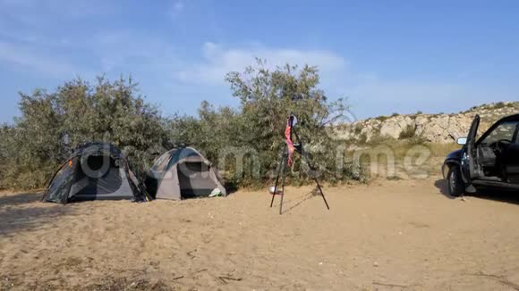 旅游营地帐篷和一辆汽车在旅游停车场论摄影师悬挂泳衣的三脚架移动视频的预览图