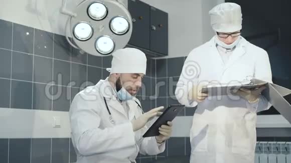两名医生在诊所的平板电脑和笔记本上登记了一个数据4K视频的预览图