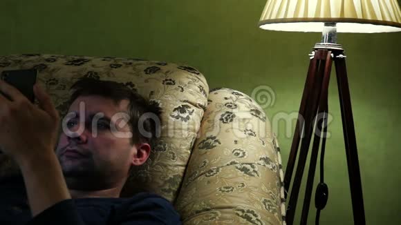 男人在沙发上看智能手机才睡着视频的预览图