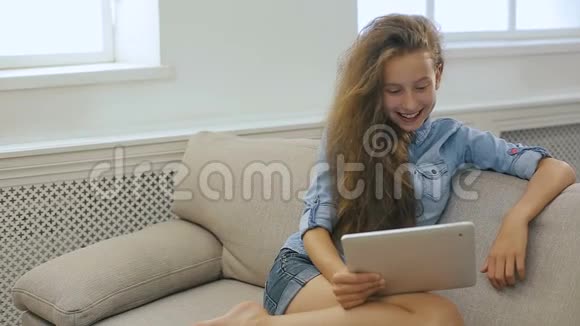 坐在沙发上的少女正在从平板电脑上看书微笑着竖起大拇指视频的预览图