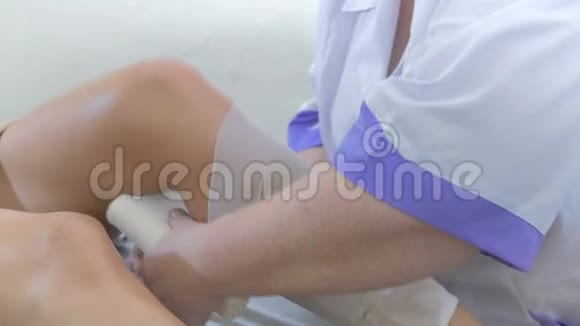 一个女人在美容院用绷带包扎一个女孩腿视频的预览图