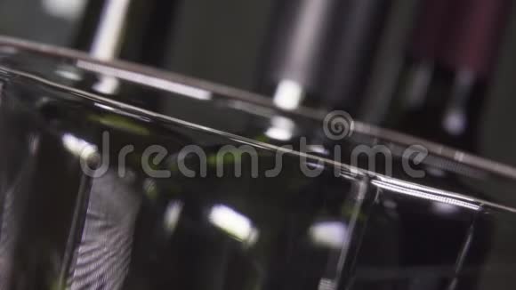 葡萄酒在瓶子的背景下倒入玻璃杯中视频的预览图