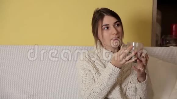 一个年轻的女孩穿着一件舒适温暖的毛衣在冬天的晚上在家喝茶想些什么视频的预览图