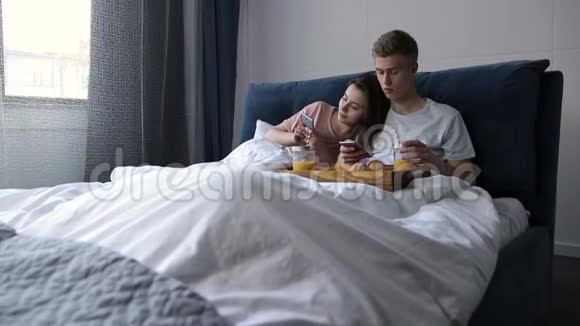 床上有智能手机的可爱情侣上网视频的预览图