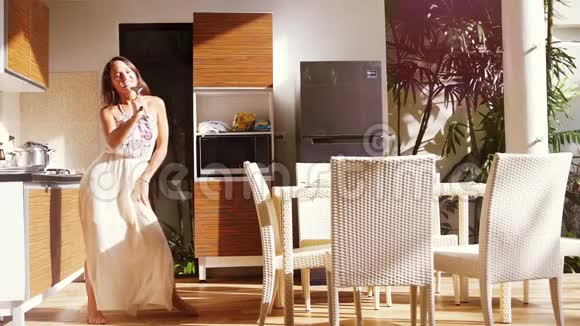 快乐的年轻女人在厨房做饭时唱歌跳舞180fps超慢动作1920x1080视频的预览图