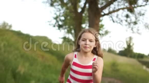 一个漂亮的卷发女孩穿着红色条纹连衣裙沿着小路跑前景动态视频稳定性视频的预览图
