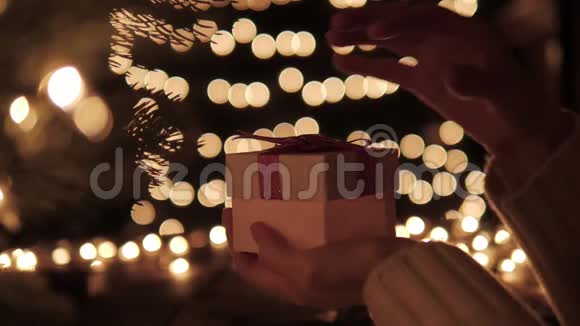 女士打开白色圣诞礼品盒在bokeh灯背景上有一束神奇的光线视频的预览图
