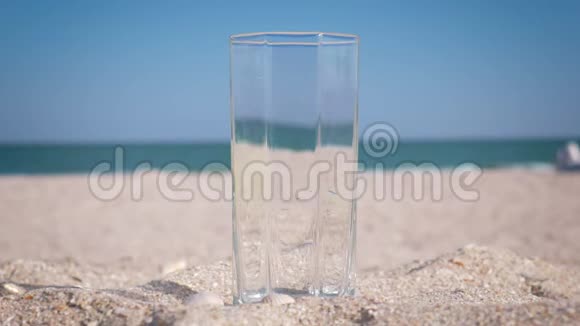 玻璃矗立在沙滩上装满饮用水背景是大海特写视频的预览图