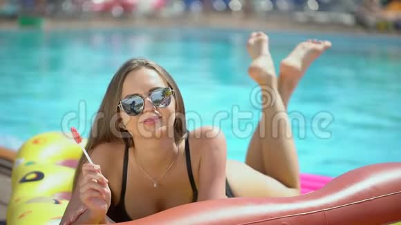 年轻女子20多岁在暑假在游泳池附近放松比基尼女孩日光浴躺在充气床垫上视频的预览图