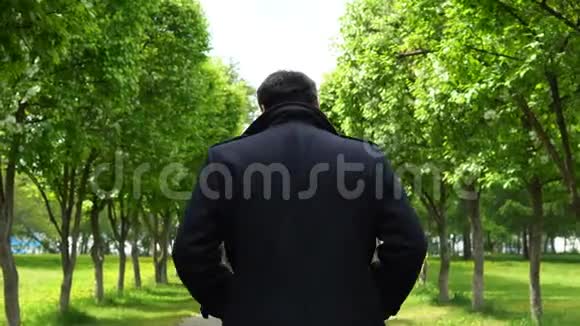 一个年轻人沿着公园的小巷散步视频的预览图