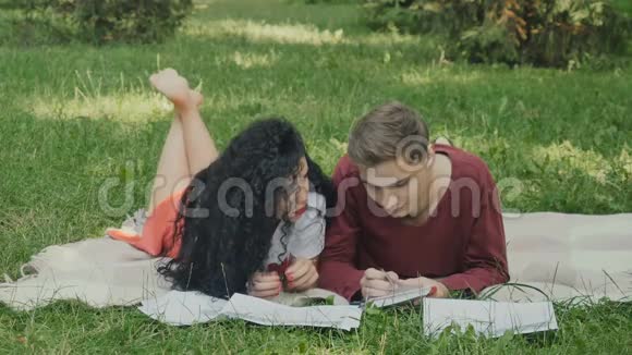 年轻的女孩和男孩准备在格子花呢的夏季公园参加考试视频的预览图