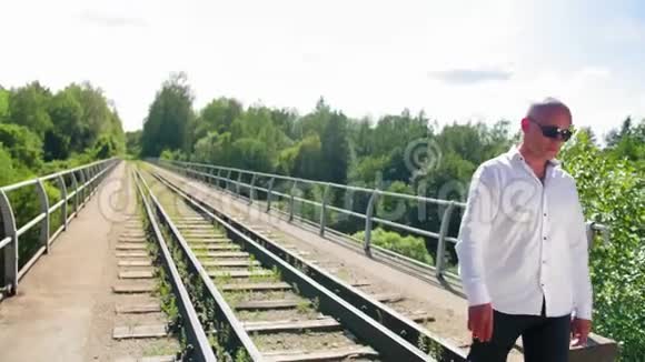 一个秃顶的人在一座废弃的铁路桥上唱歌近距离射击视频的预览图