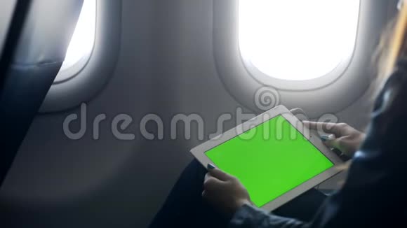 女士双手拿着平板电脑坐在飞机上视频的预览图