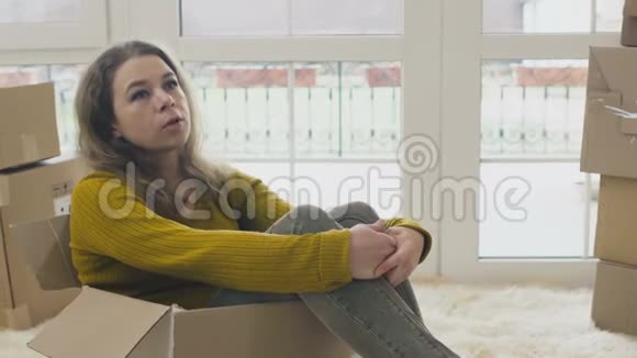 女人坐在空盒子里在新房子里规划新生活视频的预览图