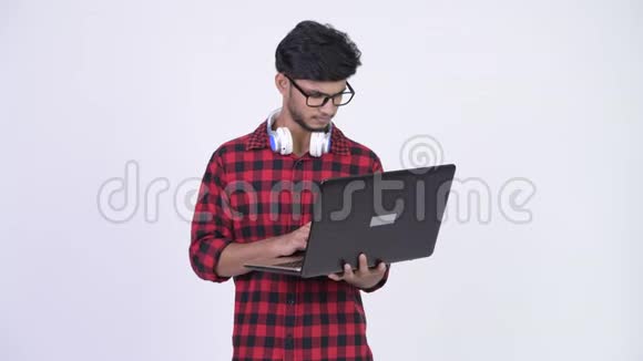 年轻英俊的留着胡子的印度嬉皮士在用笔记本电脑思考问题视频的预览图