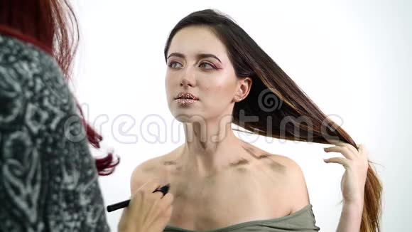 化妆师在白色化妆间将液体色调基础涂在女孩的脖子上美容和时尚概念视频的预览图