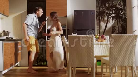 年轻迷人的快乐夫妇在家里的厨房里做饭时玩得很开心接吻跳舞3840x2160视频的预览图