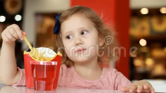 小女孩在咖啡馆里吃快餐薯条和喝果汁视频的预览图