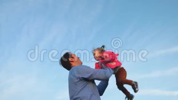 爸爸把婴儿扔进了蓝天爸爸把婴儿扔起来幸福家庭的概念爸爸和女儿在公园玩视频的预览图