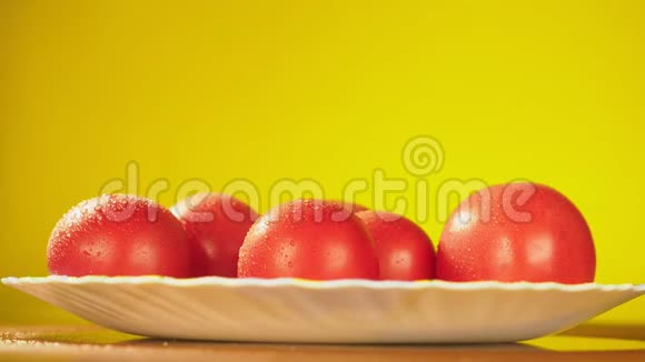 手拿着新鲜的西红柿从盘子里拿出一滴水营养的概念在黄色的叶子上视频的预览图