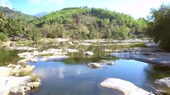 河流中的大石头对抗热带树木和山脉视频的预览图