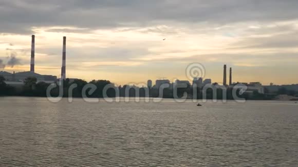 飞机正降落在工业烟囱和日落的背景上从船上漂浮的景色视频的预览图