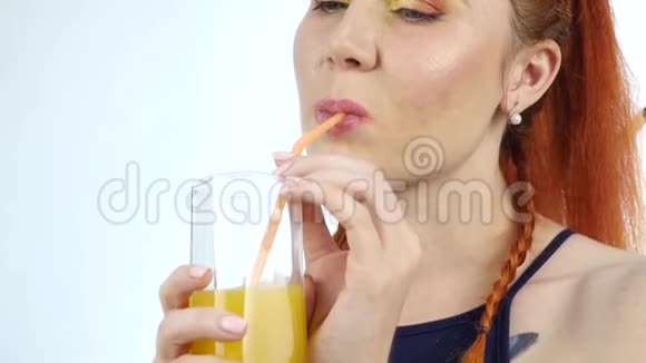 年轻女子在灯光背景下享受和喝橙汁慢动作视频的预览图
