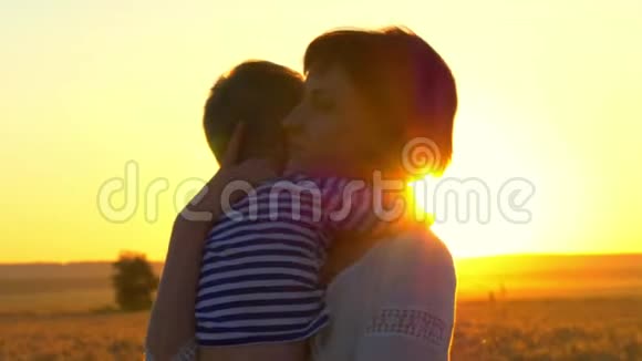 一位快乐的母亲抱着她的孩子在夕阳下的麦田里幸福家庭的概念视频的预览图