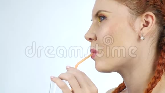 年轻女子在灯光背景下享受和喝橙汁慢动作视频的预览图