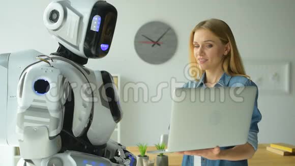 手持笔记本电脑的年轻女士与机器人讨论技术视频的预览图