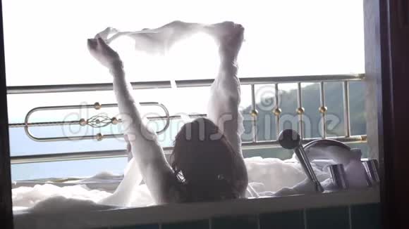后景为沐浴的黑发女人在浴缸里放松泡沫在热带度假胜地享受女孩水疗视频的预览图