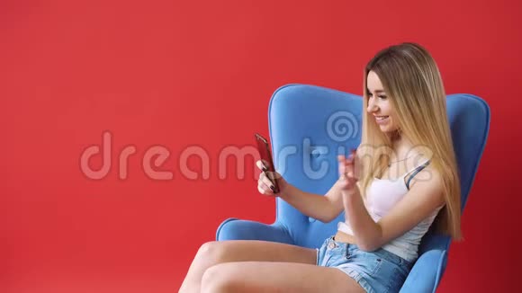 红墙背景上的女孩在电话视频短信广播中交谈视频的预览图
