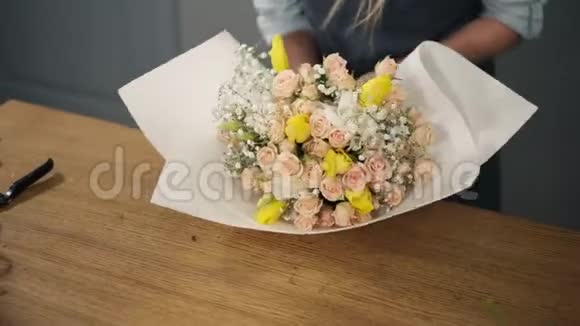 年轻的金发女郎花店把一束花包在装饰纸上视频的预览图