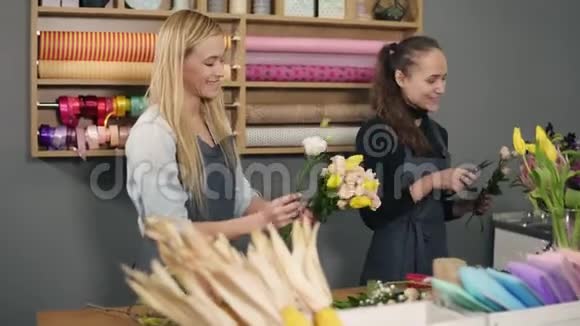 穿着围裙的金发碧眼的花匠站在花店柜台旁一边整理着一束鲜花视频的预览图