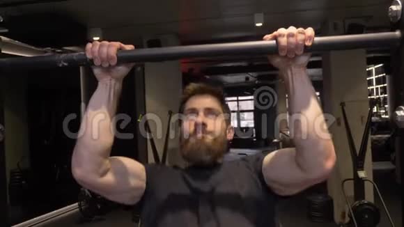 健身馆里的成年肌肉健美运动员在酒吧里举起自己的特写镜头视频的预览图
