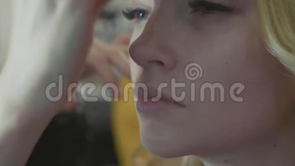 年轻的化妆师把遮瑕膏涂在模特脸上视频的预览图